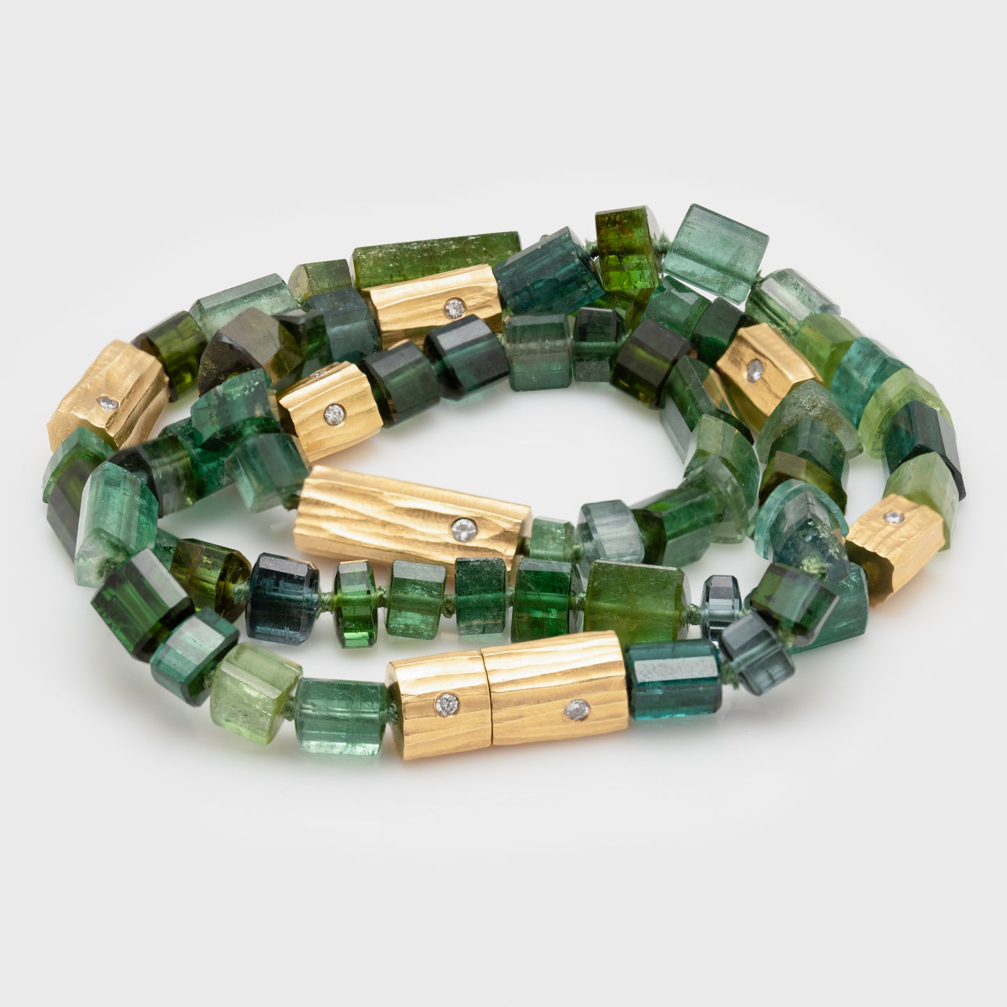 Close-up, a necklace with barrel-shaped green tourmaline beads, 18k yellow gold, and redwood bark clasp with diamonds.