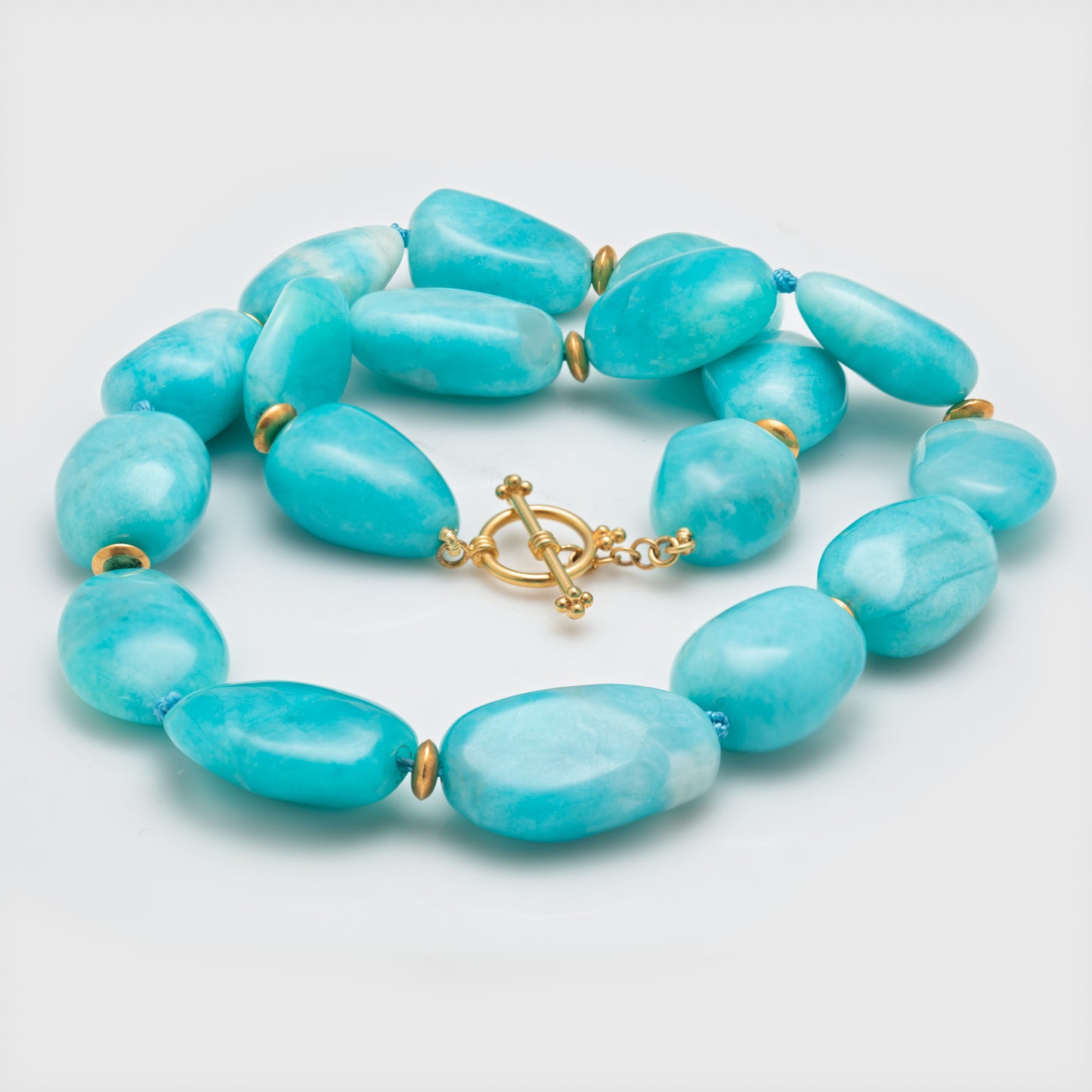 Close-up of an amazonite necklace with 22k yellow gold accents and toggle.