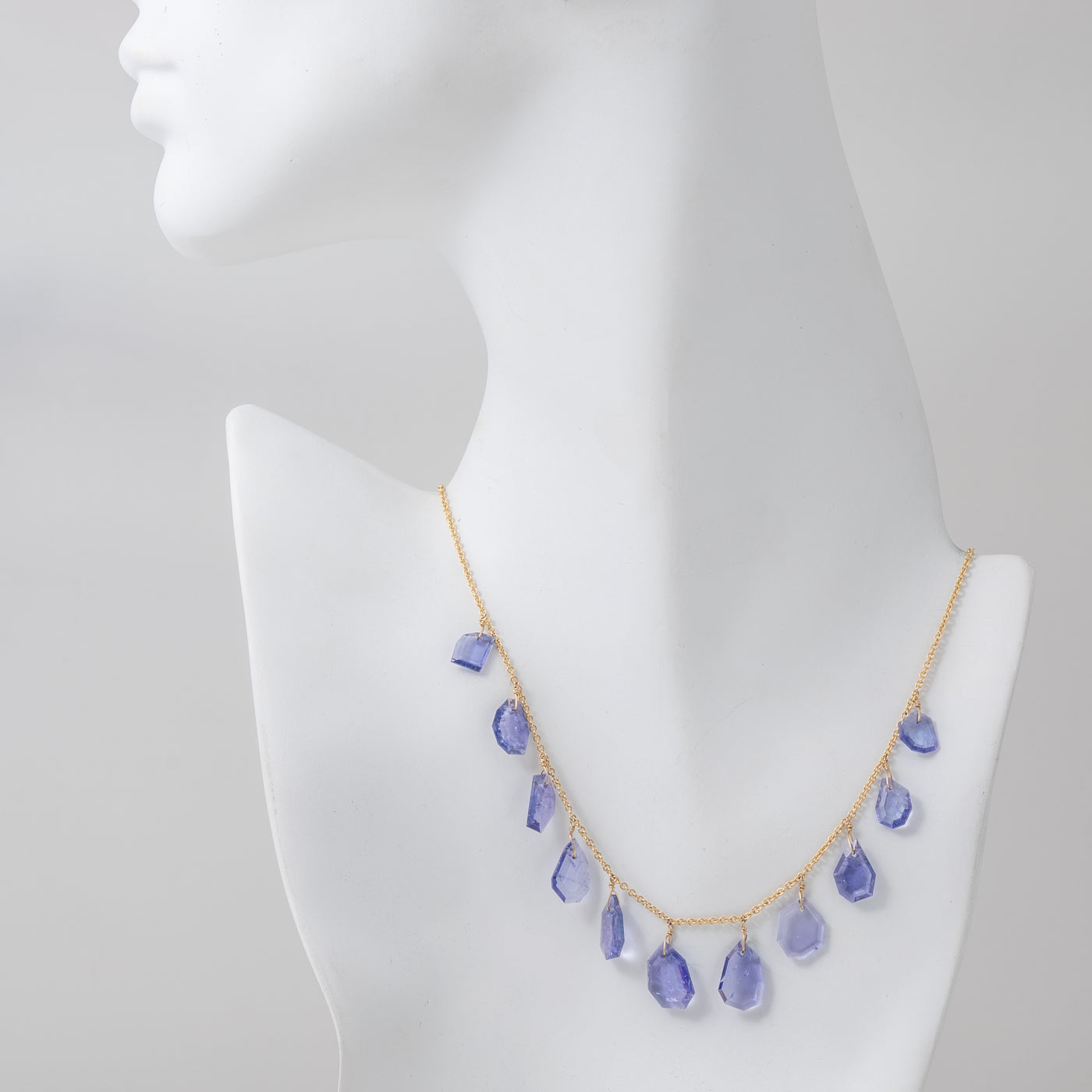 Tanzanite necklace with gold chain on a mannequin.