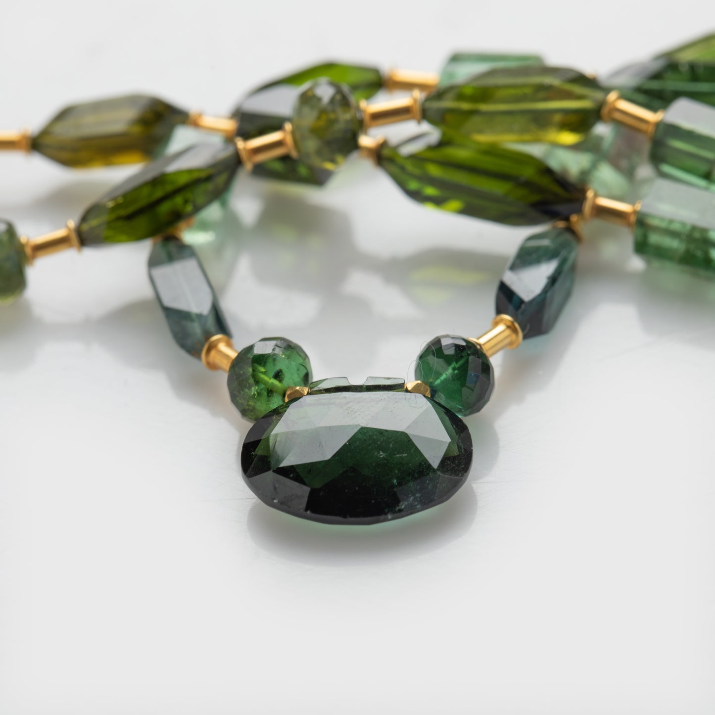 Close-up of an 18k yellow gold necklace with tourmaline.