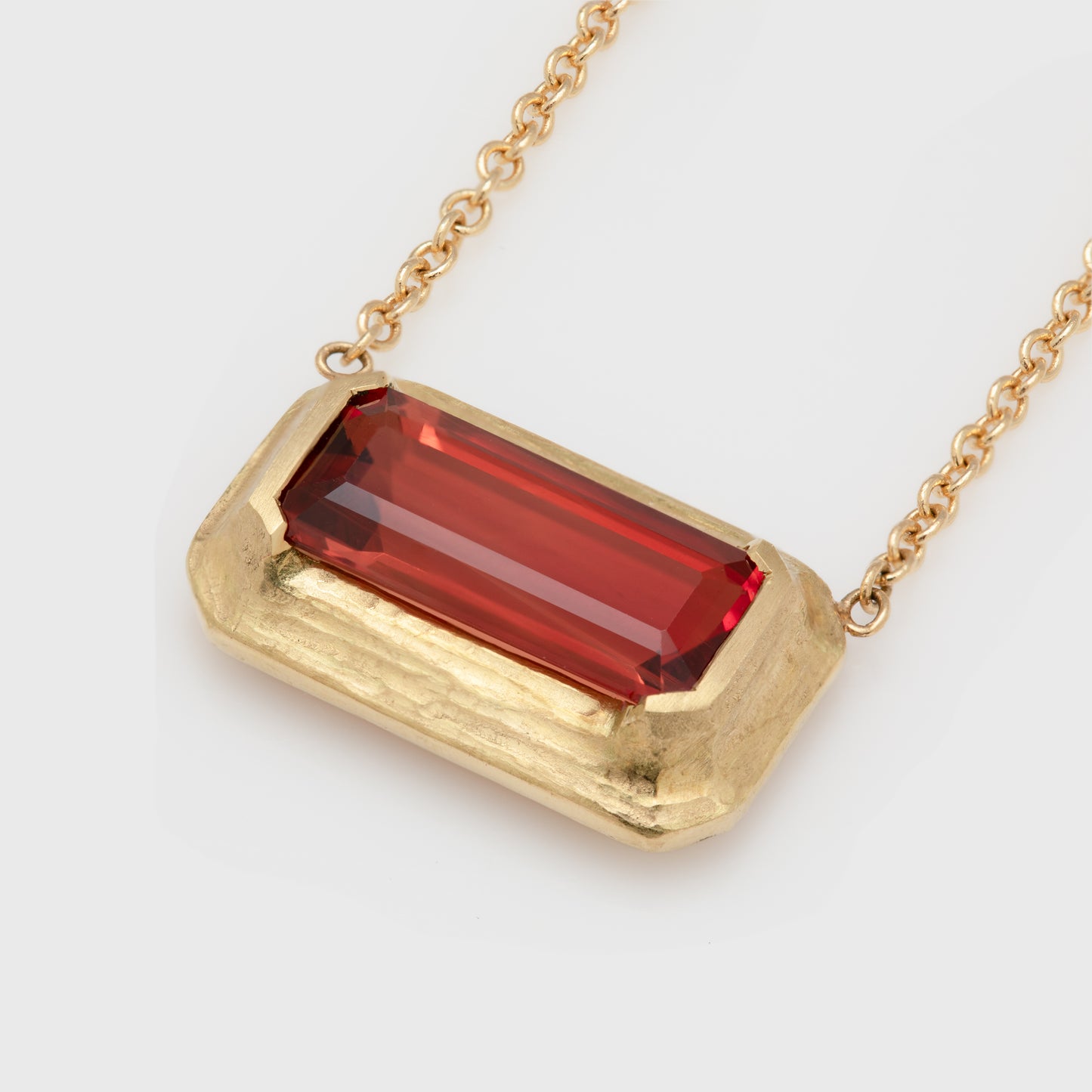 Close-up of an 18k yellow gold necklace with an emerald cut sunstone.