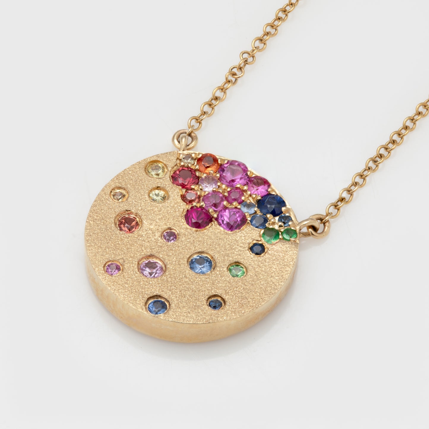 Close-up of a necklace in 14k yellow gold with faceted round sapphires and tsavorite garnets.