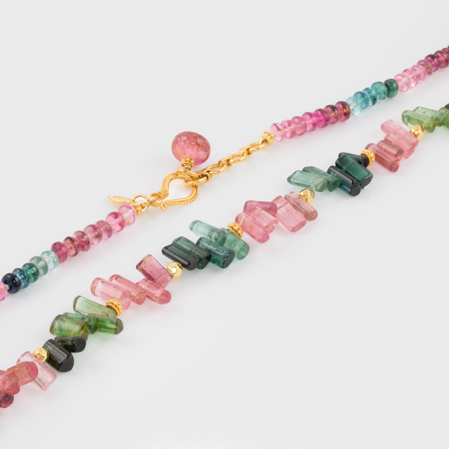 Close-up of a 18k yellow gold necklace with stick-shaped tourmaline beads.