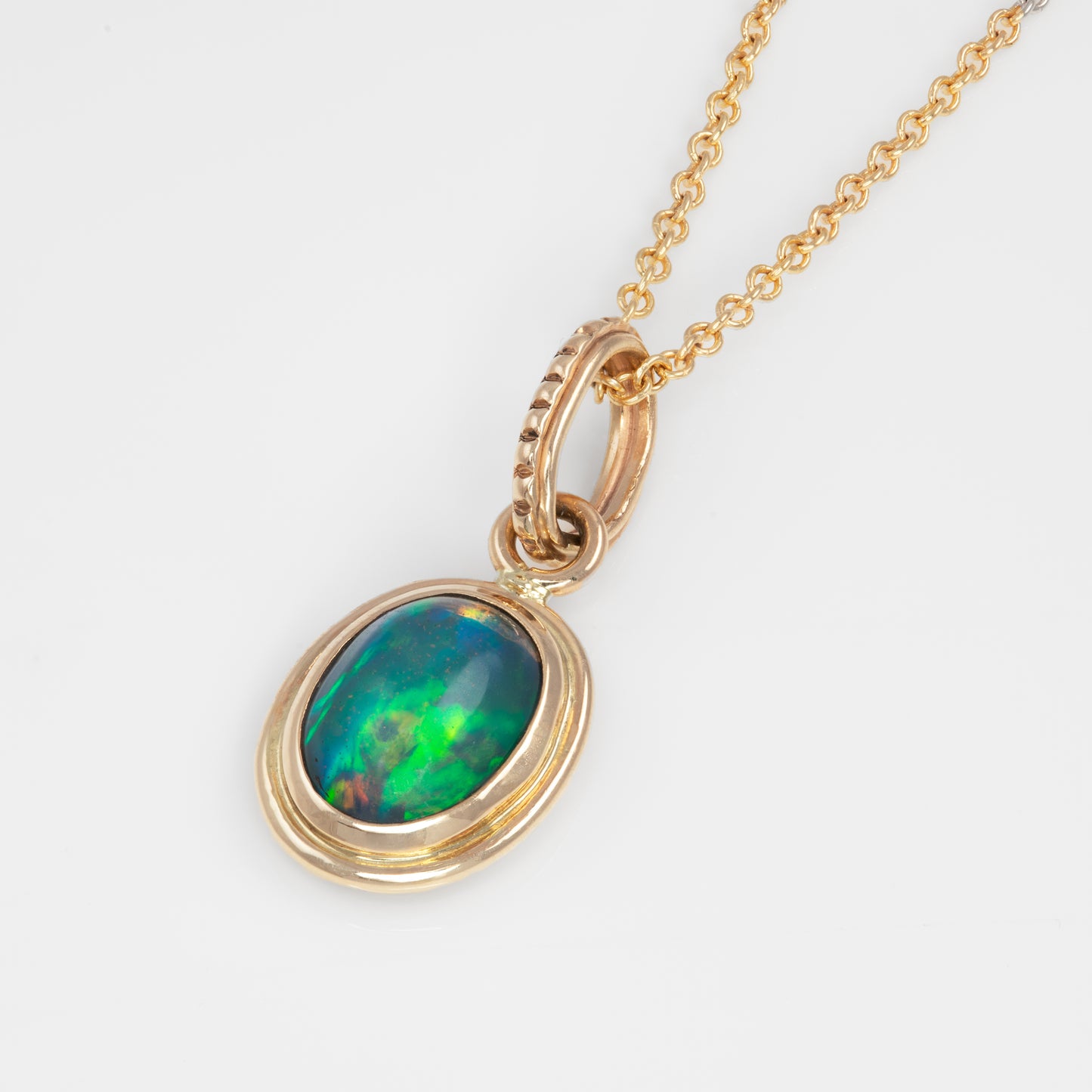 Gold pendant with green and blue opal stone on a white background