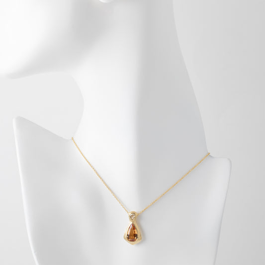 Gold necklace with a yellow orange topaz gemstone and an accent diamonds on a white mannequin background