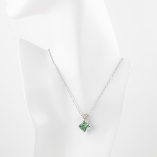 Platinum pendant with green gemstone on a white mannequin