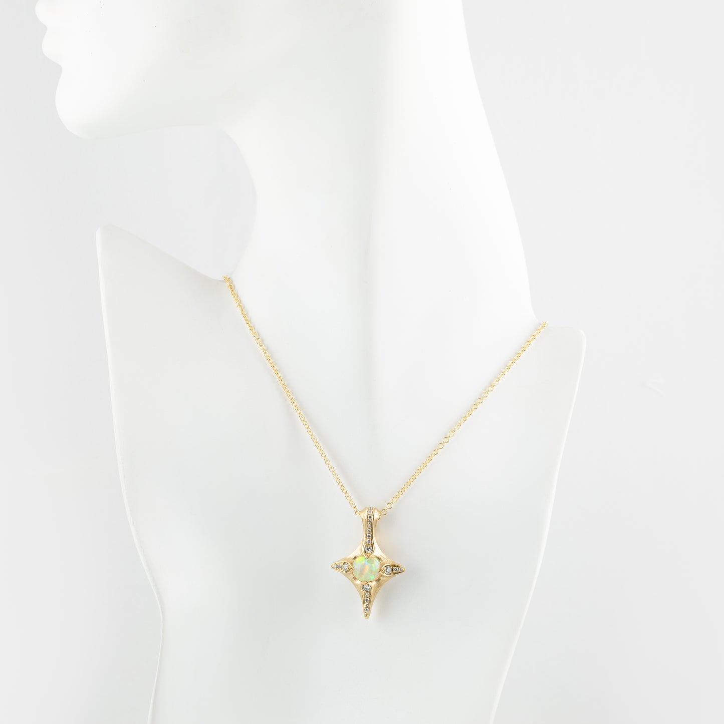 Gold necklace with a opal pendant on a mannequin bust against a white background