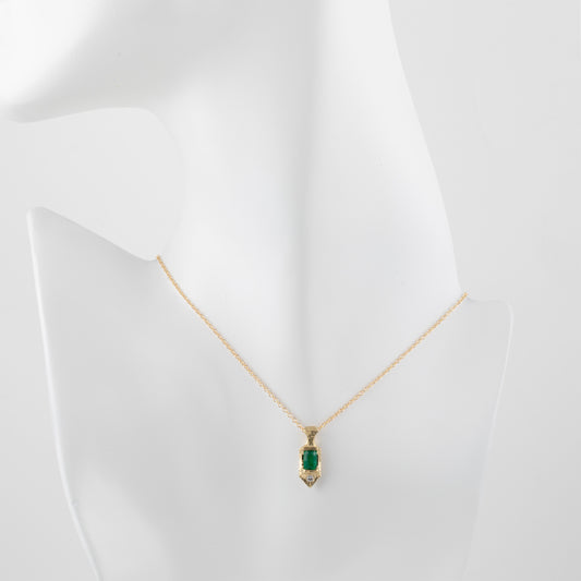 Gold necklace with a green gemstone pendant on a mannequin bust.