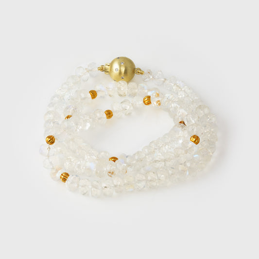Moonstone beaded bracelet with gold accents on a light gray background