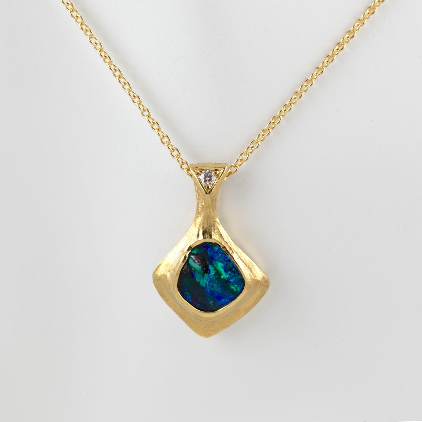 Gold natural texture necklace with a blue and green opal gemstone and accent diamond on a white background, front view