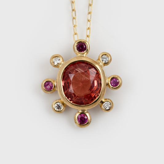 Yellow gold pendant featuring faceted oval orange pink Spinel with pink Sapphire and white Diamond accents