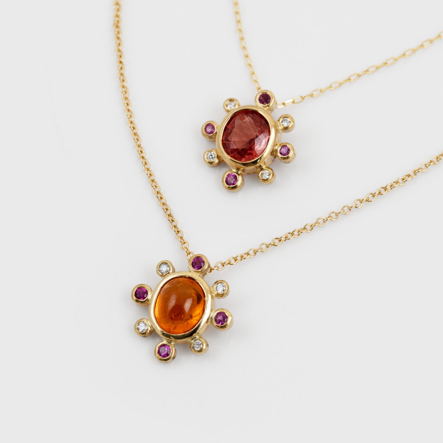 Two yellow gold necklaces with assorted orange, red, pink, and white gemstones