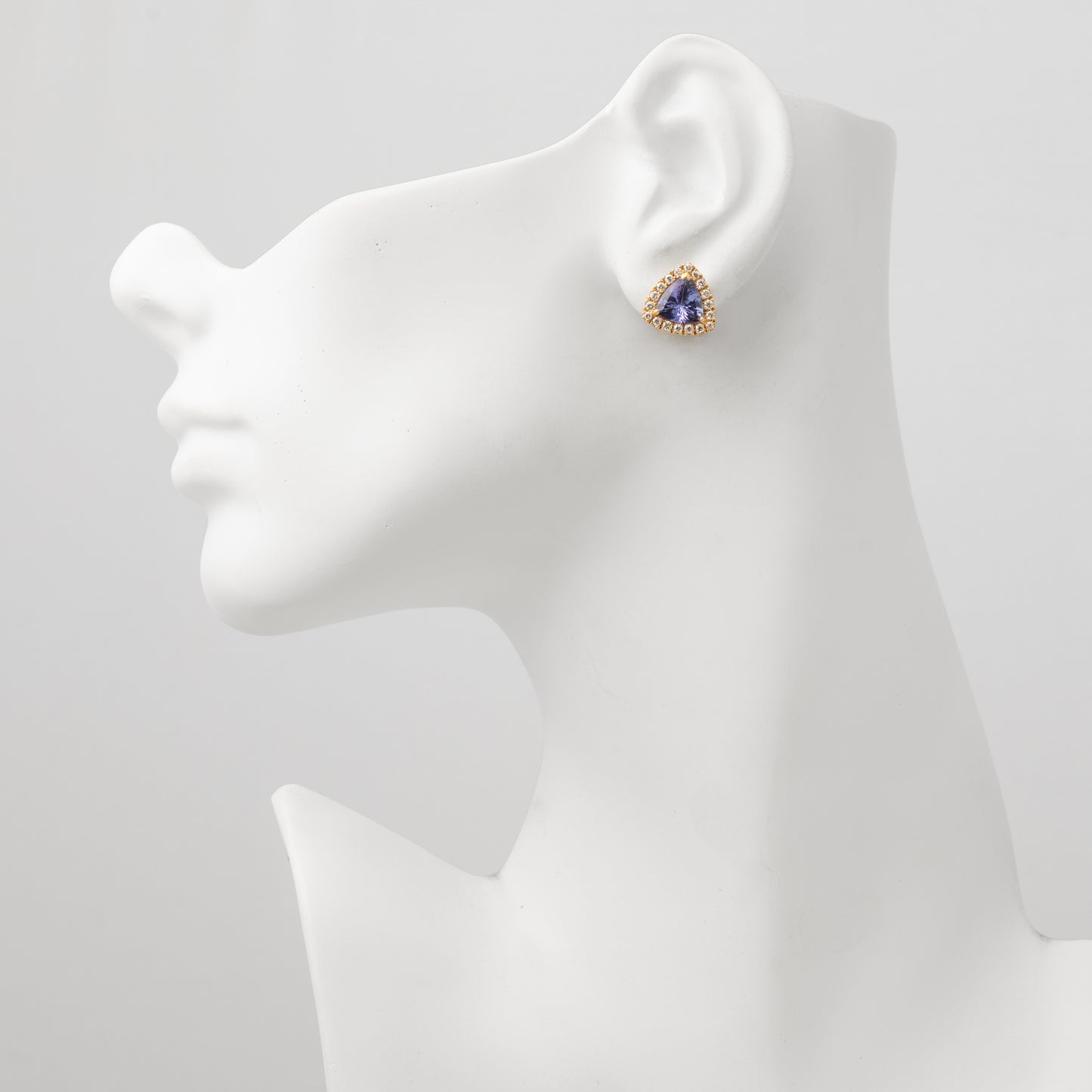 Angled view of a tanzanite halo stud earring.