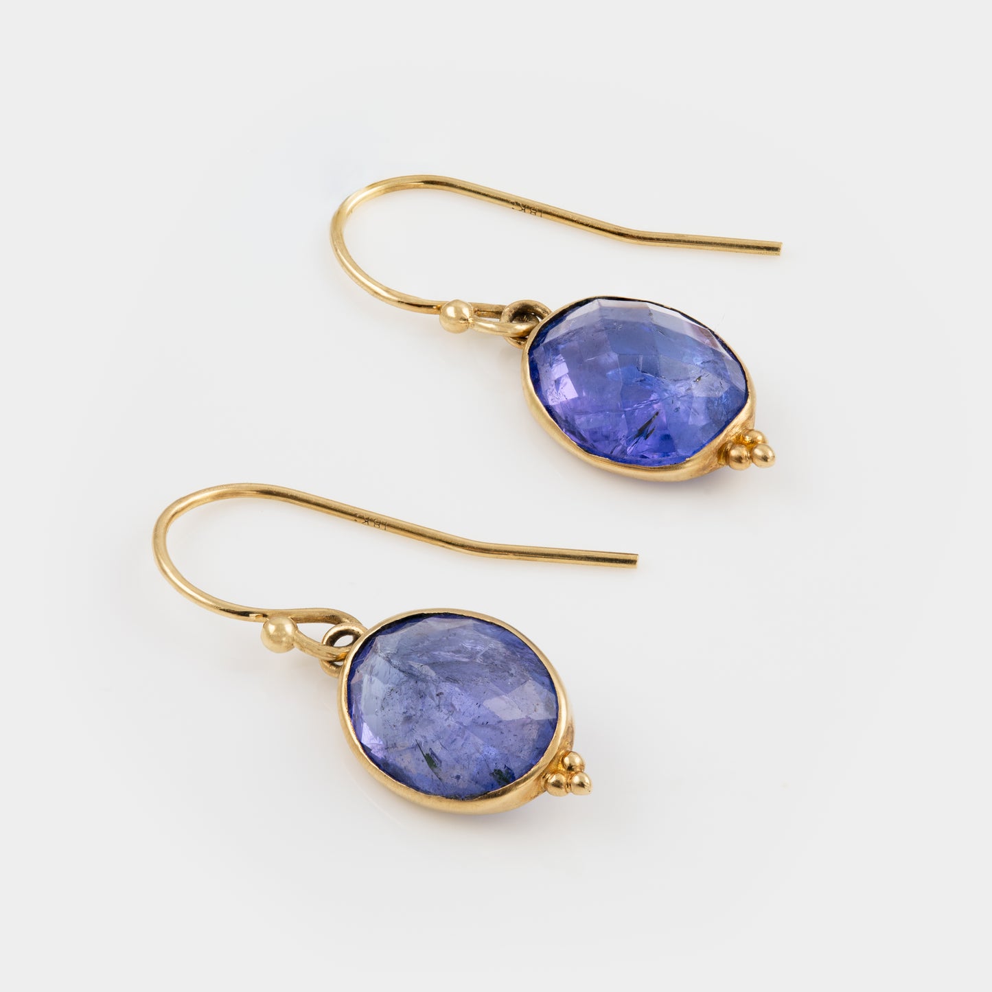 Gold earrings with Tanzanite gemstones on a white background