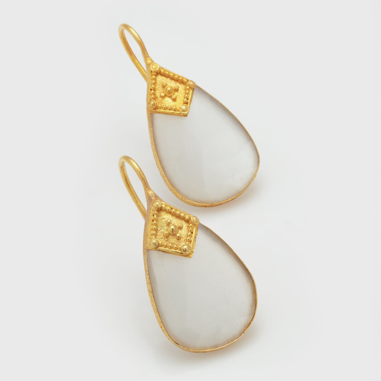 Close-up of 18k yellow gold earrings with moonstone slices.