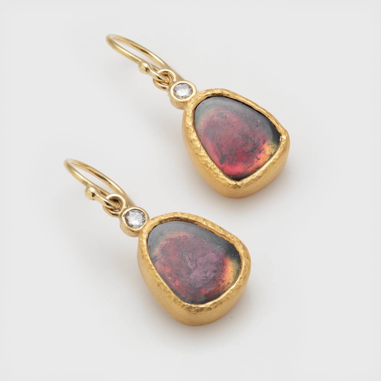 Close-up of 22k and 18k yellow gold earrings with watermelon tourmaline and round brilliant cut diamonds.