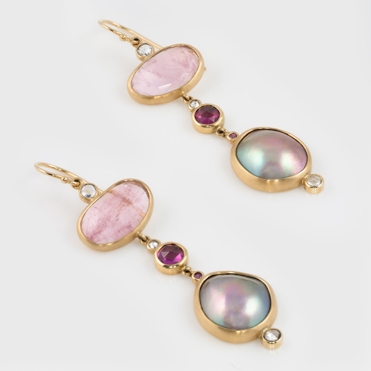 Close-up of 18k yellow gold earrings with Sea of Cortez Mabe Pearls, Morganite, Rhodolite Garnet, rose cut Diamond, and Pink Sapphires.