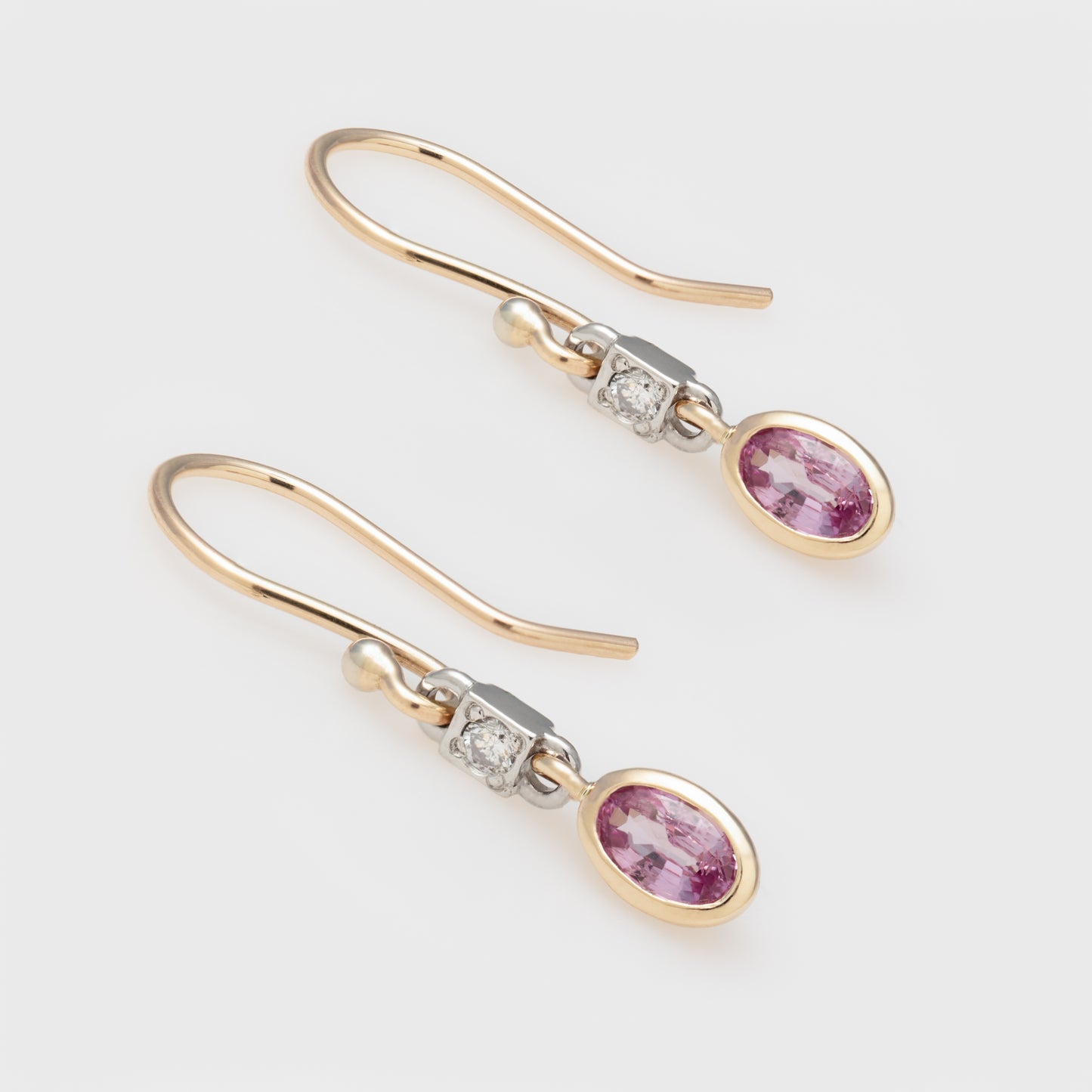 Close-up of 14k yellow gold earrings with pink sapphires and diamond accents.