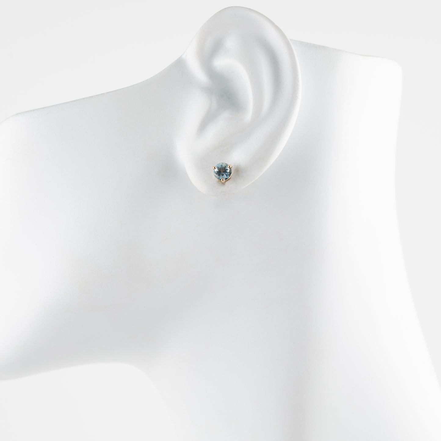 Aquamarine earring on a mannequin ear with a plain background