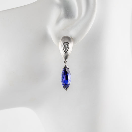 Platinum earring with a tanzanite gemstone on a mannequin ear.