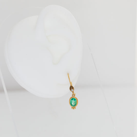 Gold earring with a green gemstone on a white background