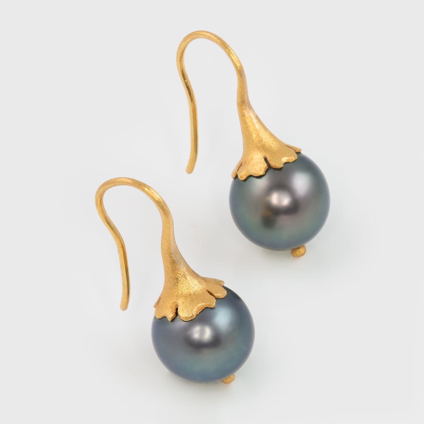 Close-up of 18k yellow gold earrings with 11mm Tahitian pearls.