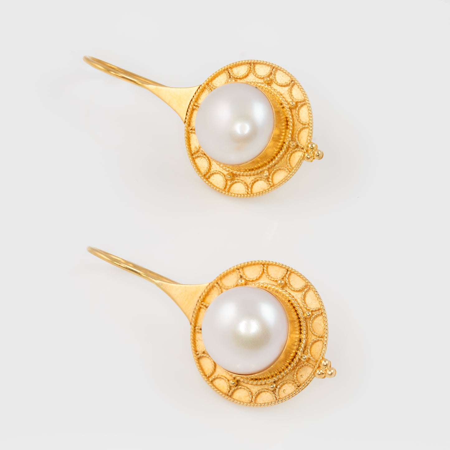 Close-up of freshwater pearl earrings in 18k yellow gold with a white freshwater pearl.