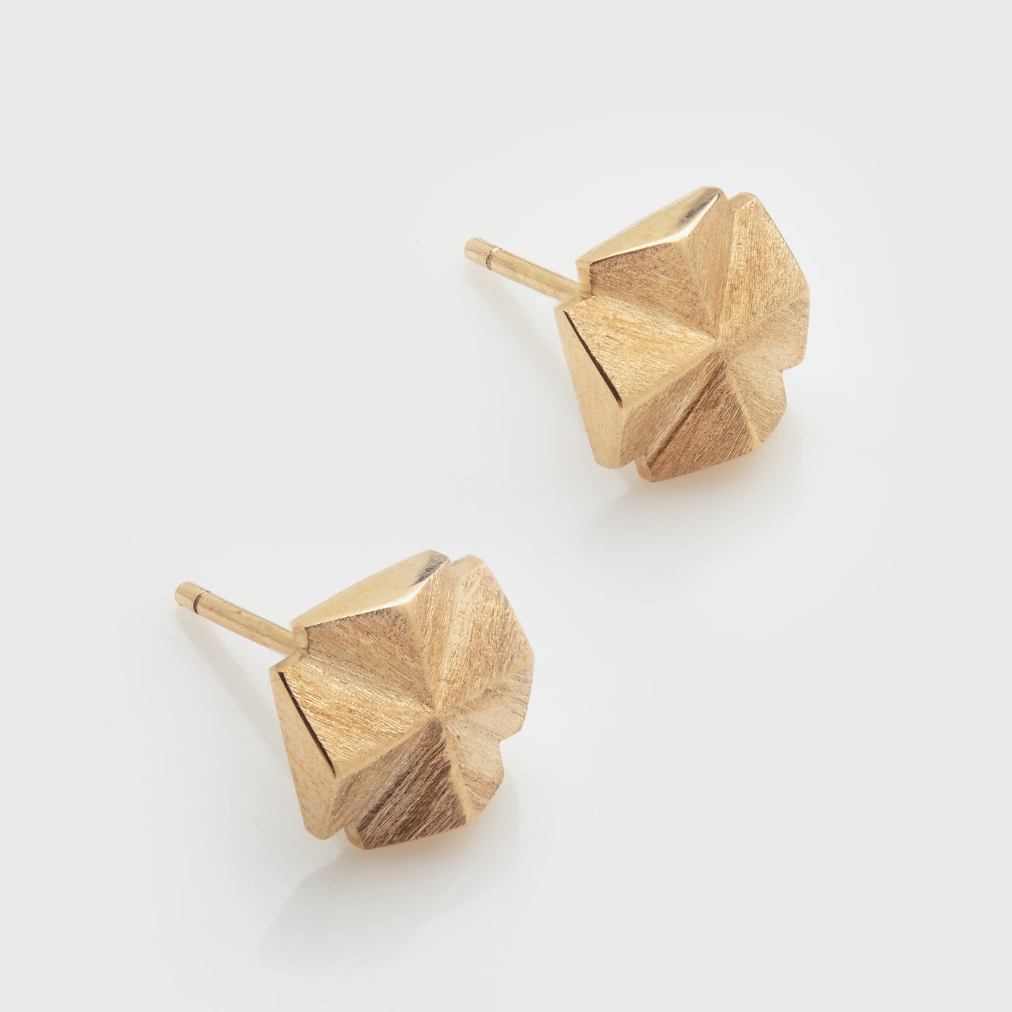 Close-up of stylized fairy cross stud earrings in 14k yellow gold with a matte finish.