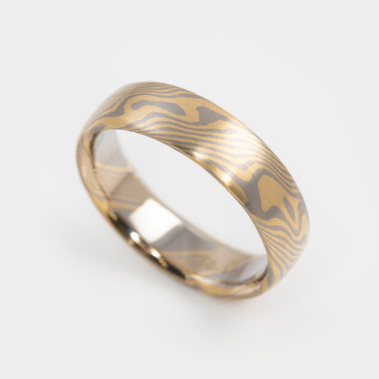 Gold and palladium ring with a mokume-gane design on a white background