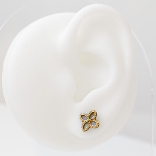 Clover-shaped earrings with gold and black design on a white earring mannequin