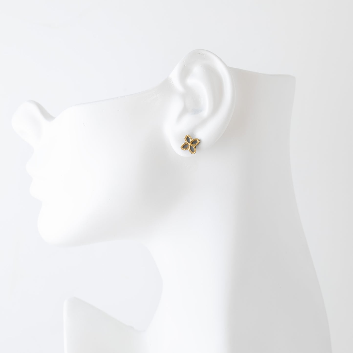 Clover-shaped earrings with gold and black design on a white mannequin