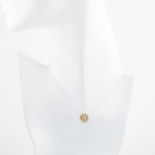 Gold and silver flower-shaped pendant on a silver chain on a white mannequin
