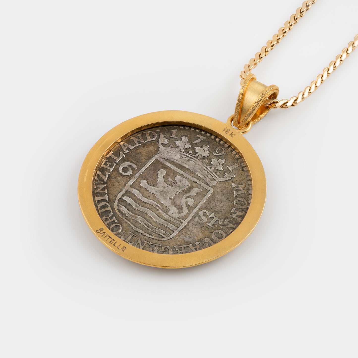 A gold pendant necklace featuring a circular coin pendant with a silver-toned lion design and gold border, suspended from a gold chain against a light gray background.