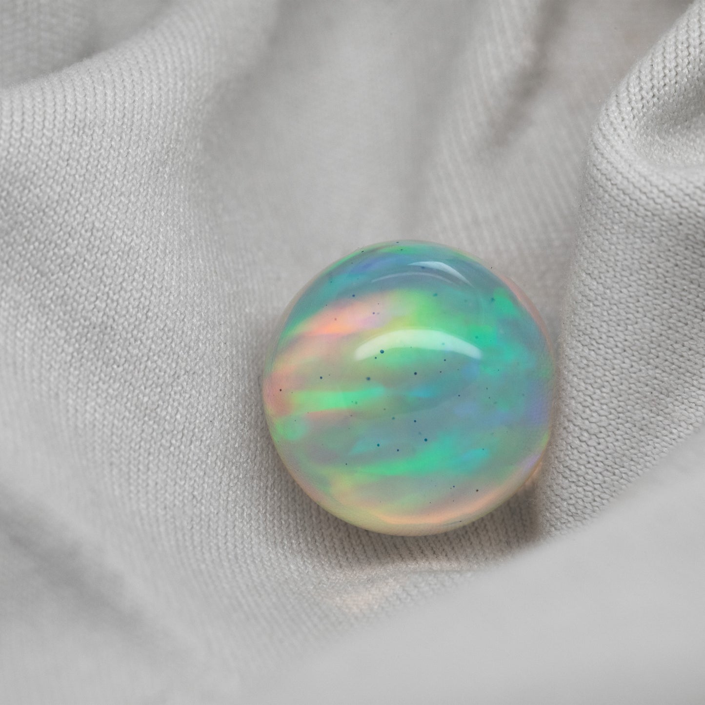 Multicolor opal sphere on a white fabric background