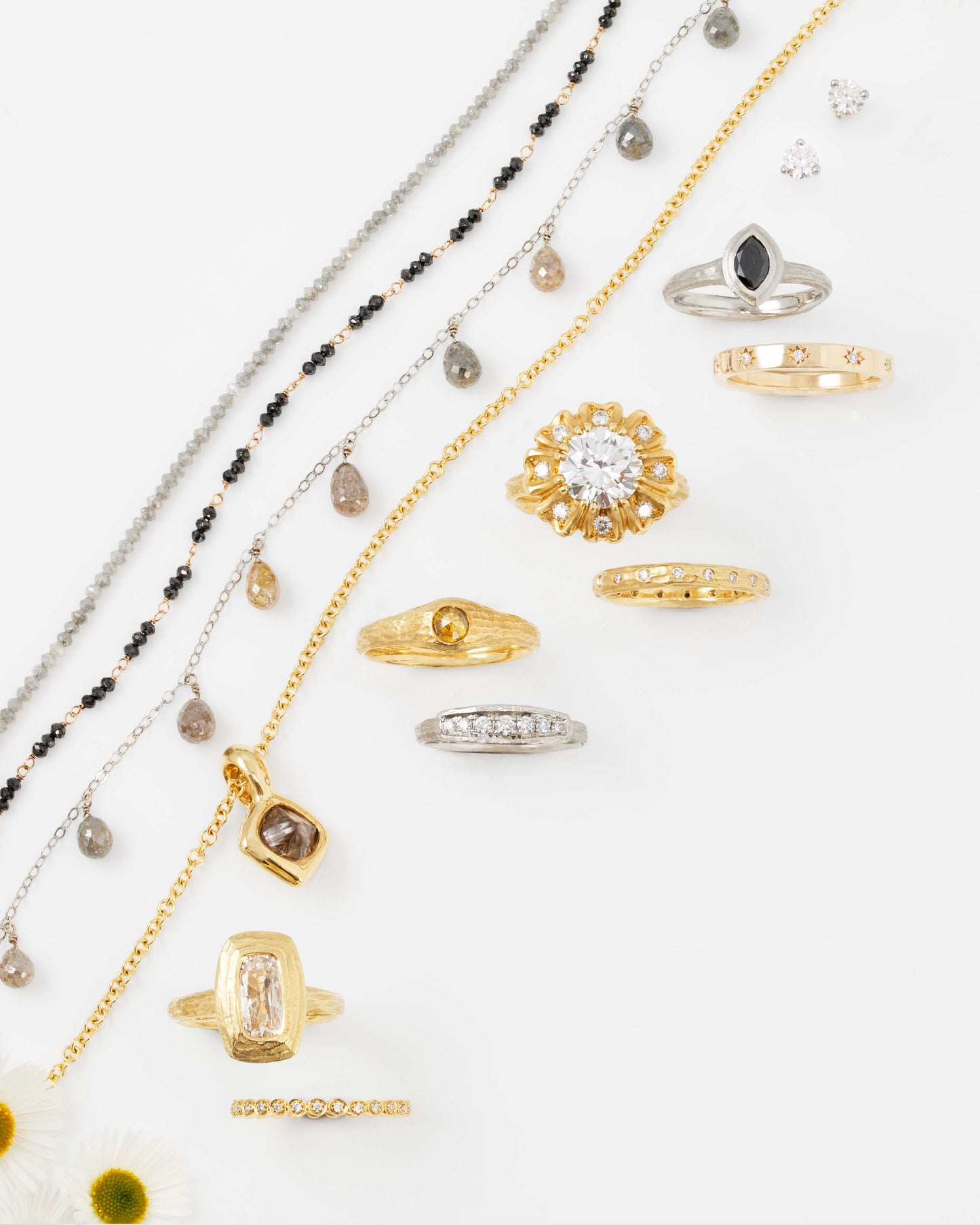 Variety of diamond bracelets, necklaces, and rings on a white background with daisies in the lower left corner