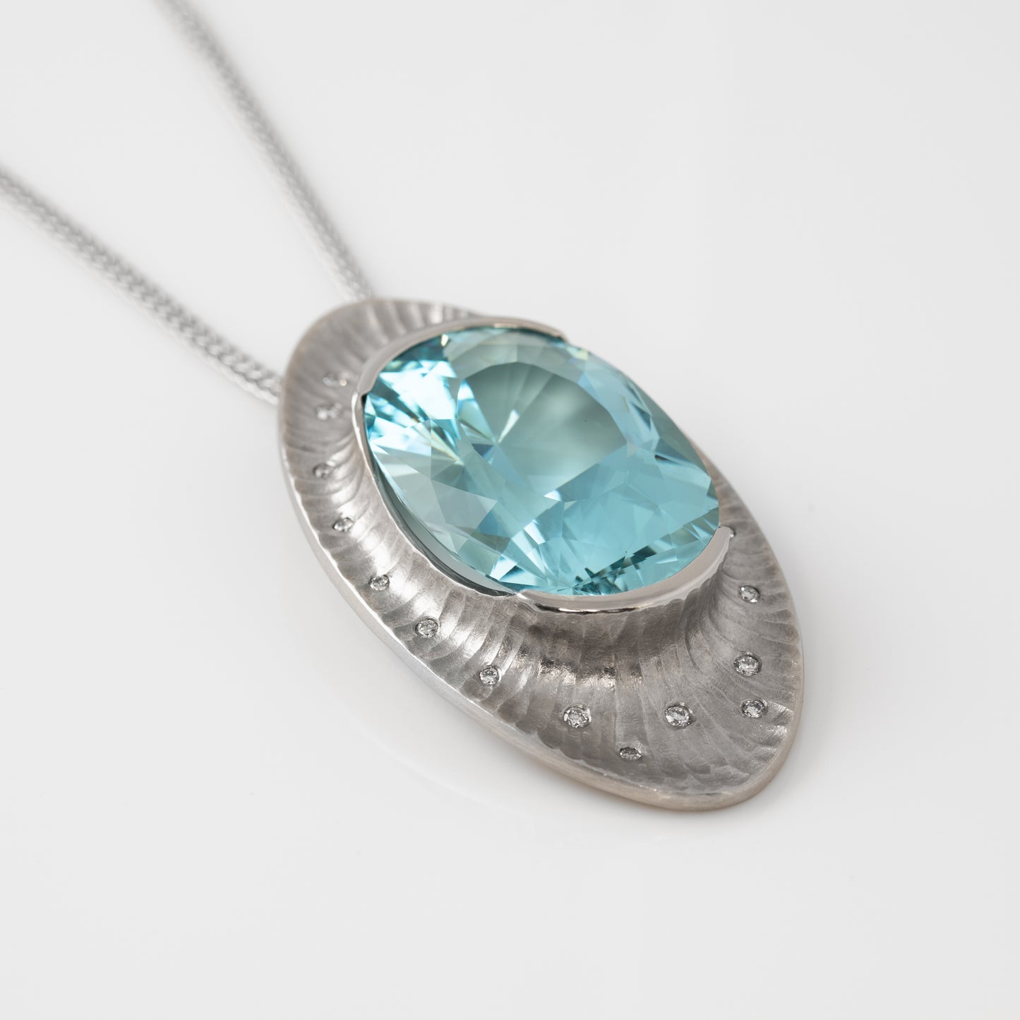 Platinum pendant with a blue gemstone on a white background, front view