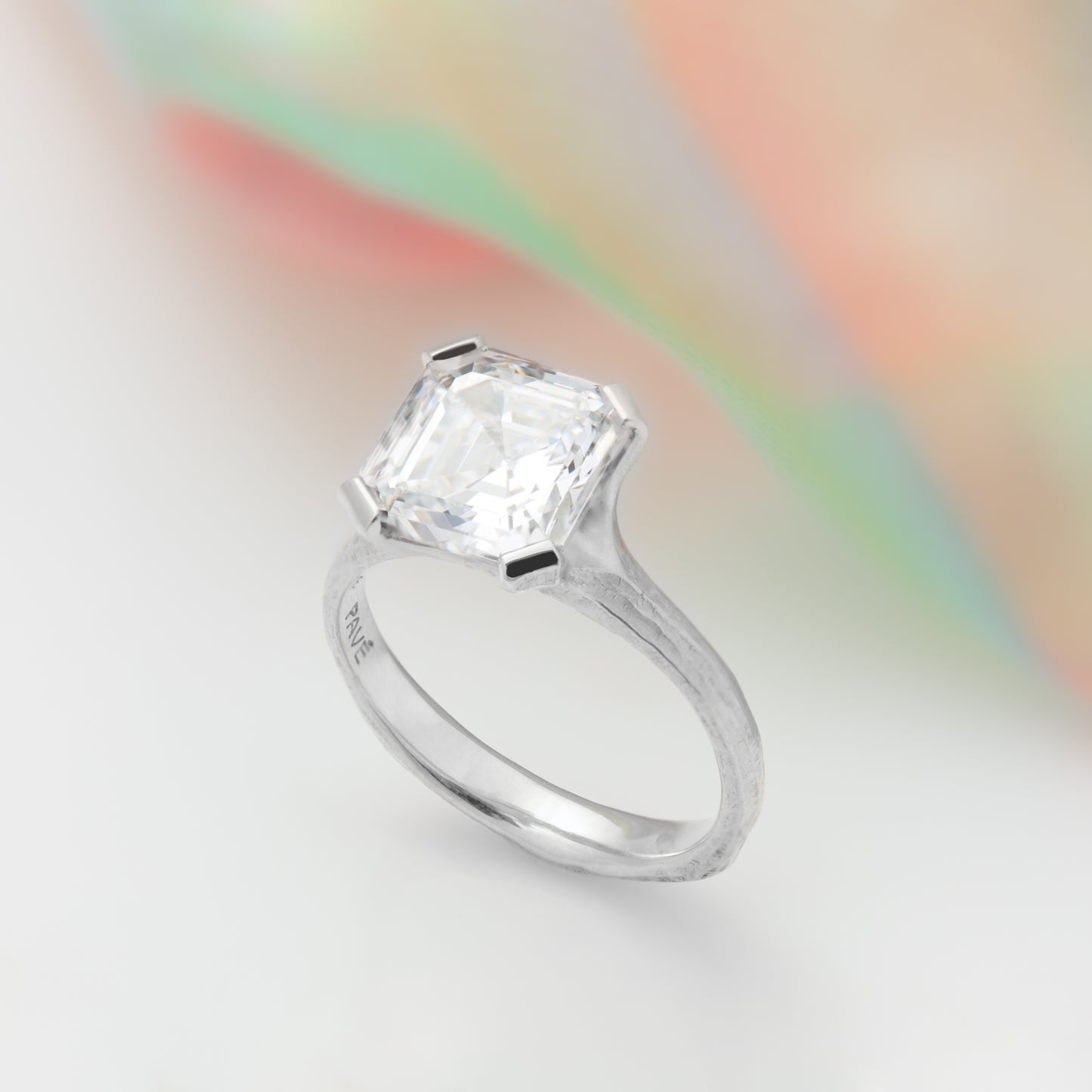 Angled view of a platinum ring with asscher diamond and redwood bark.