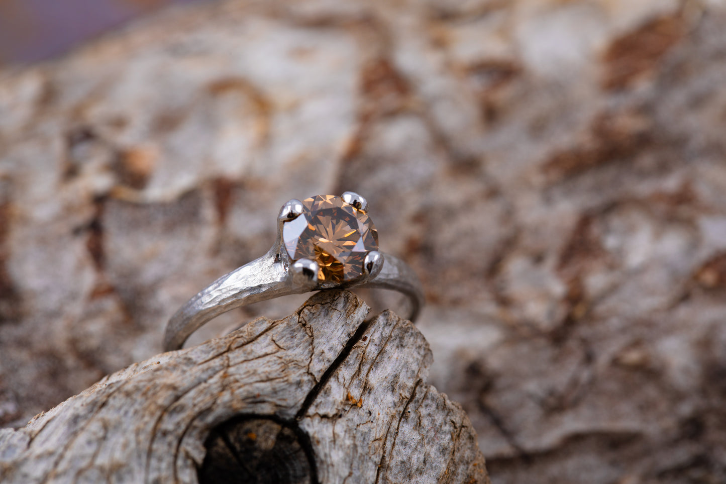 Platinum ring with a brown gemstone on a wooden surface