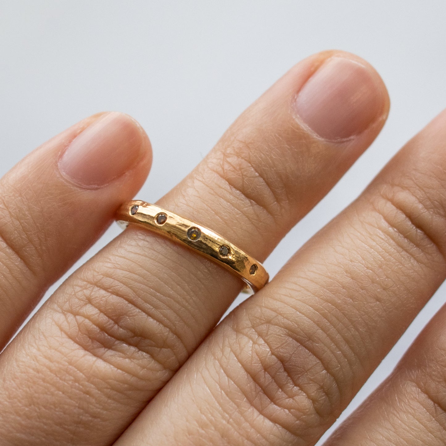 Worn on hand, an 18k rose gold band with natural autumn-colored diamonds.