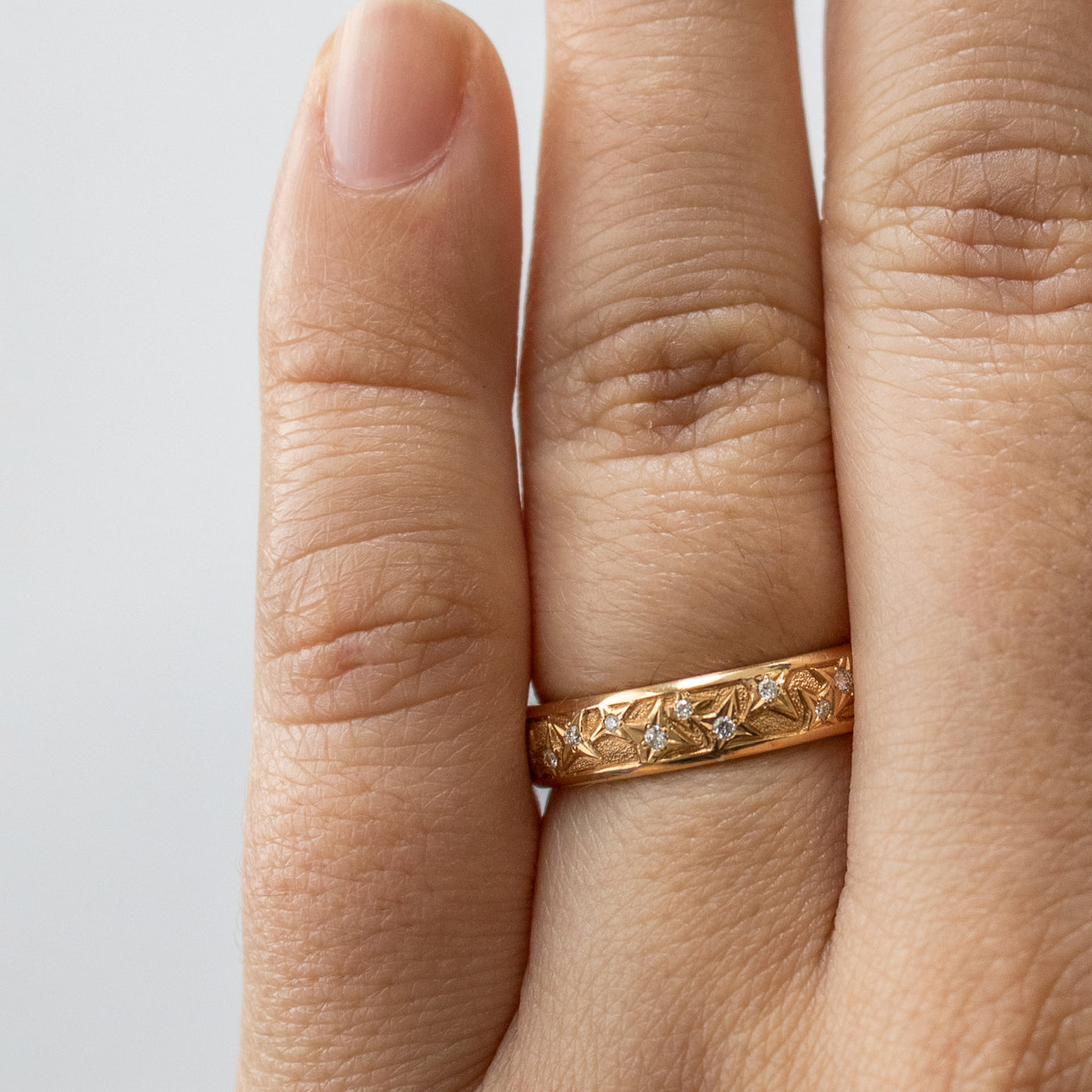Worn on hand, an 18k rose gold band with natural diamonds.