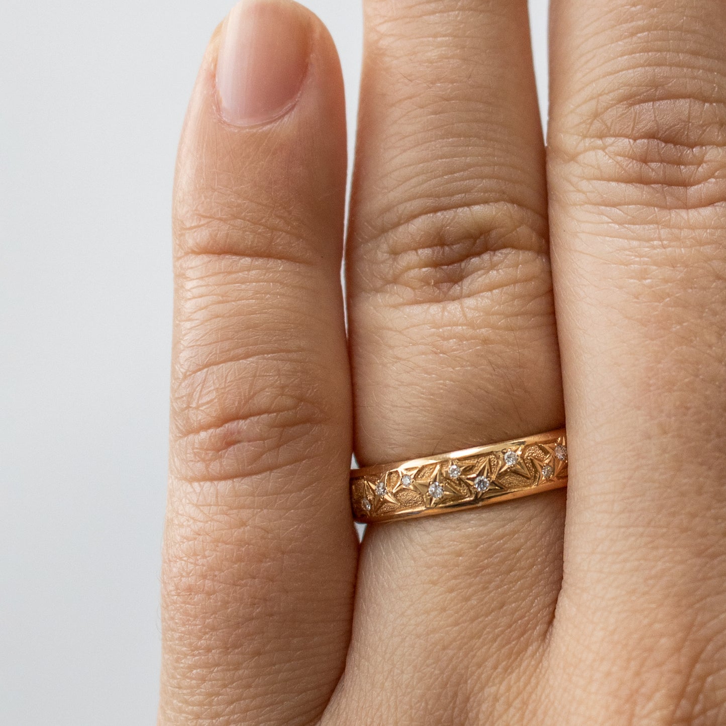 Worn on hand, an 18k rose gold band with natural diamonds.
