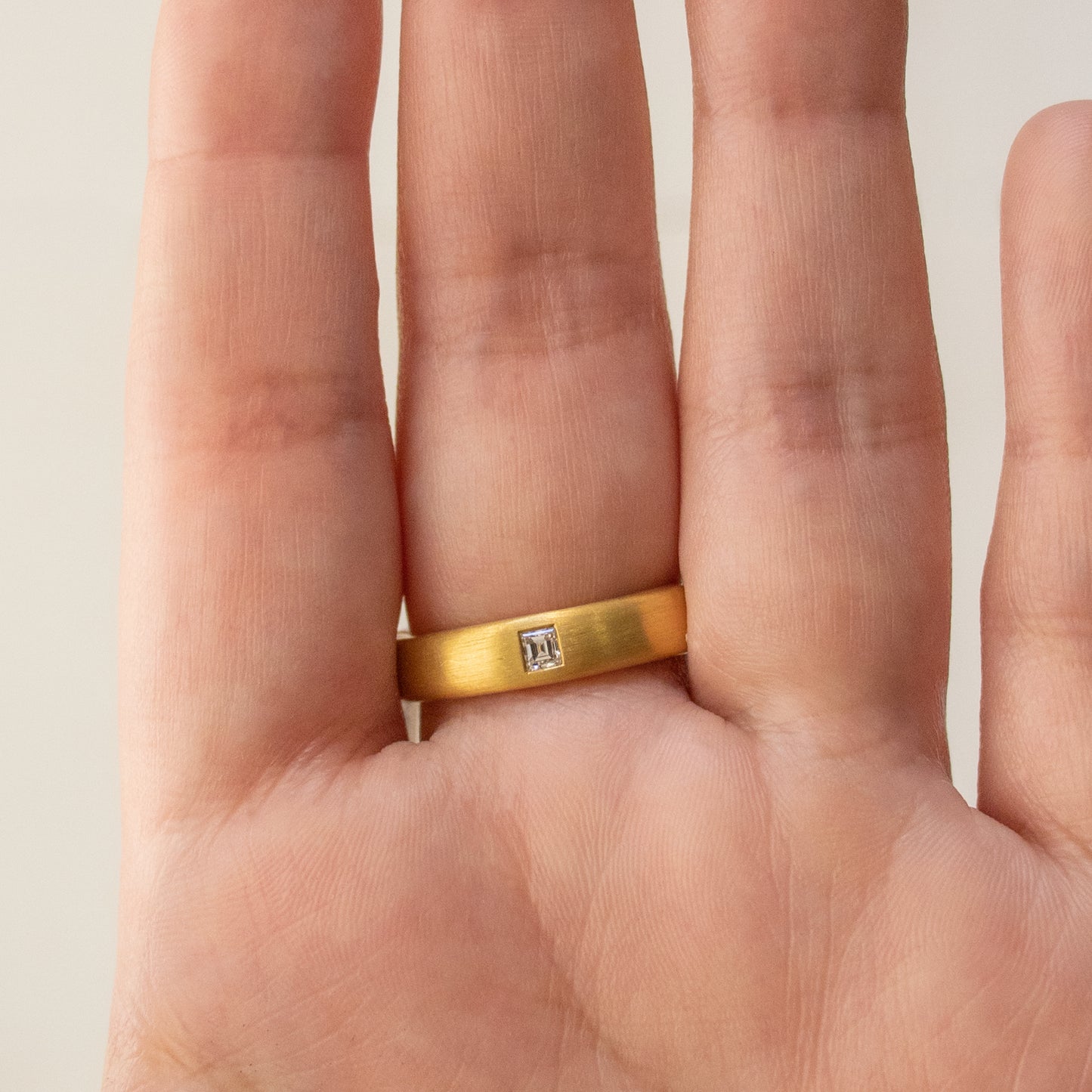 Worn on hand, a 22k yellow gold ring with tourmaline and square diamonds.