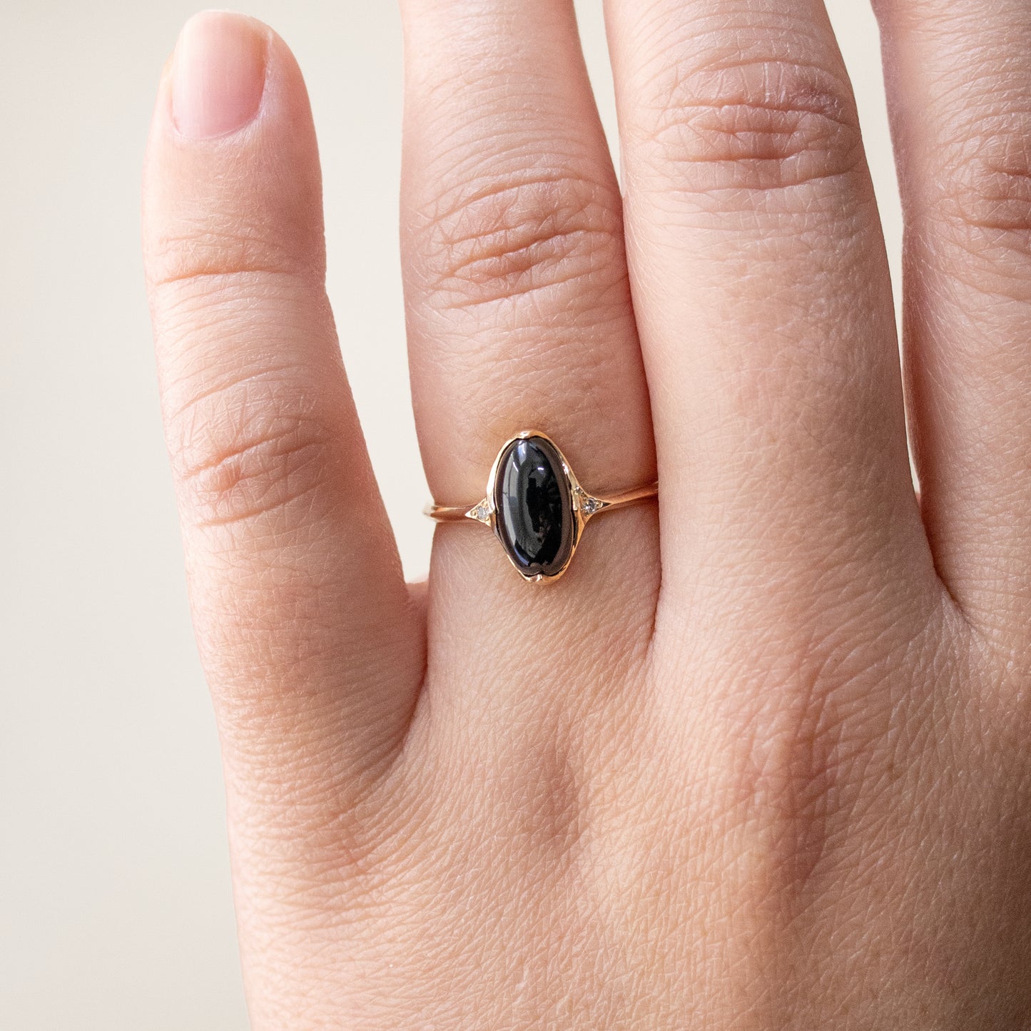 Worn on hand, a 14k yellow gold ring with black jade and diamonds.