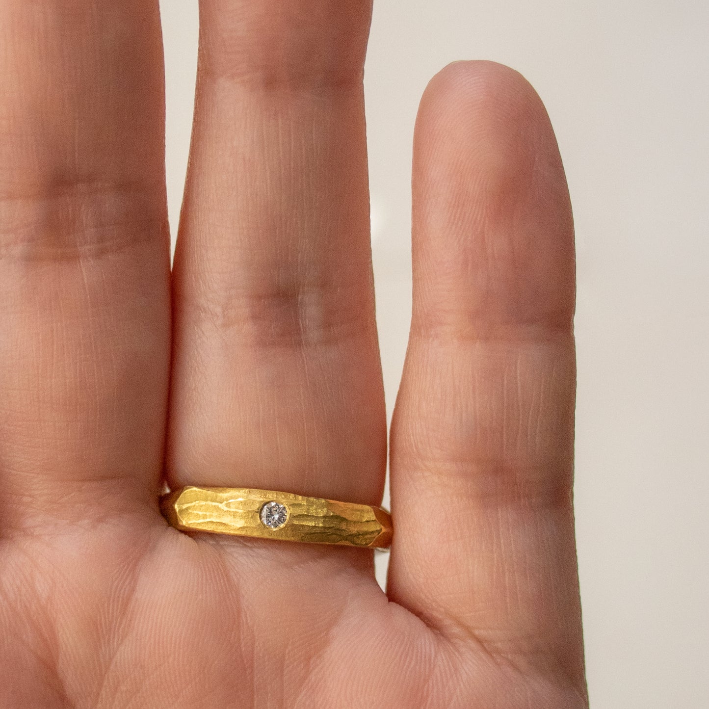 Worn on hand, a 22k yellow gold ring with natural gems, a cushion-cut deep green tourmaline and a flush-set secret diamond located on the back.