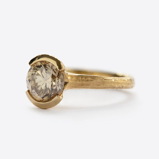 Side view of yellow metal ring with round gem
