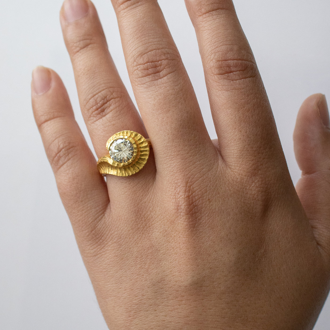 Yellow metal ring with round gem worn on a hand