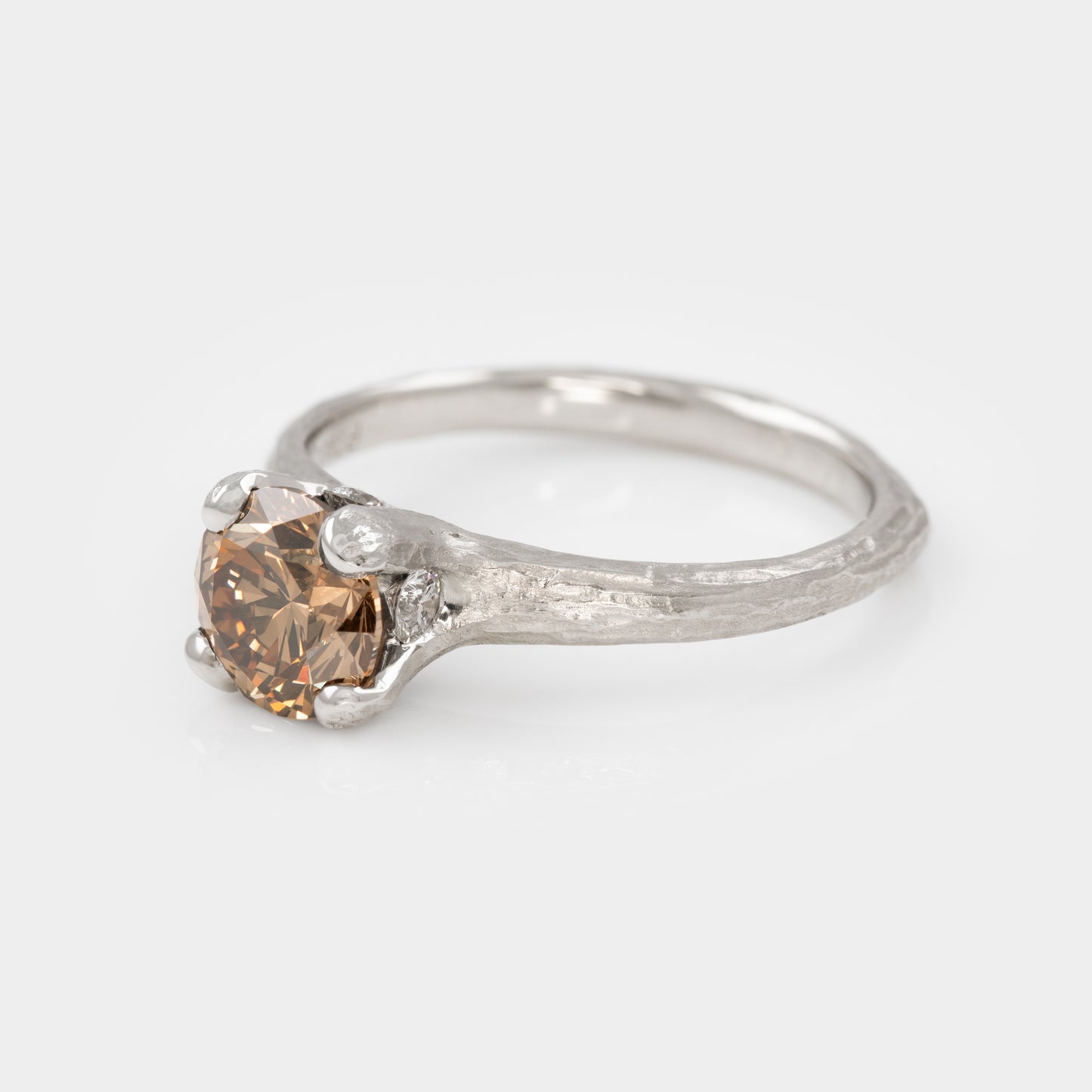 Three fourths angle of redwood bark texture platinum ring with cognac diamond on white background