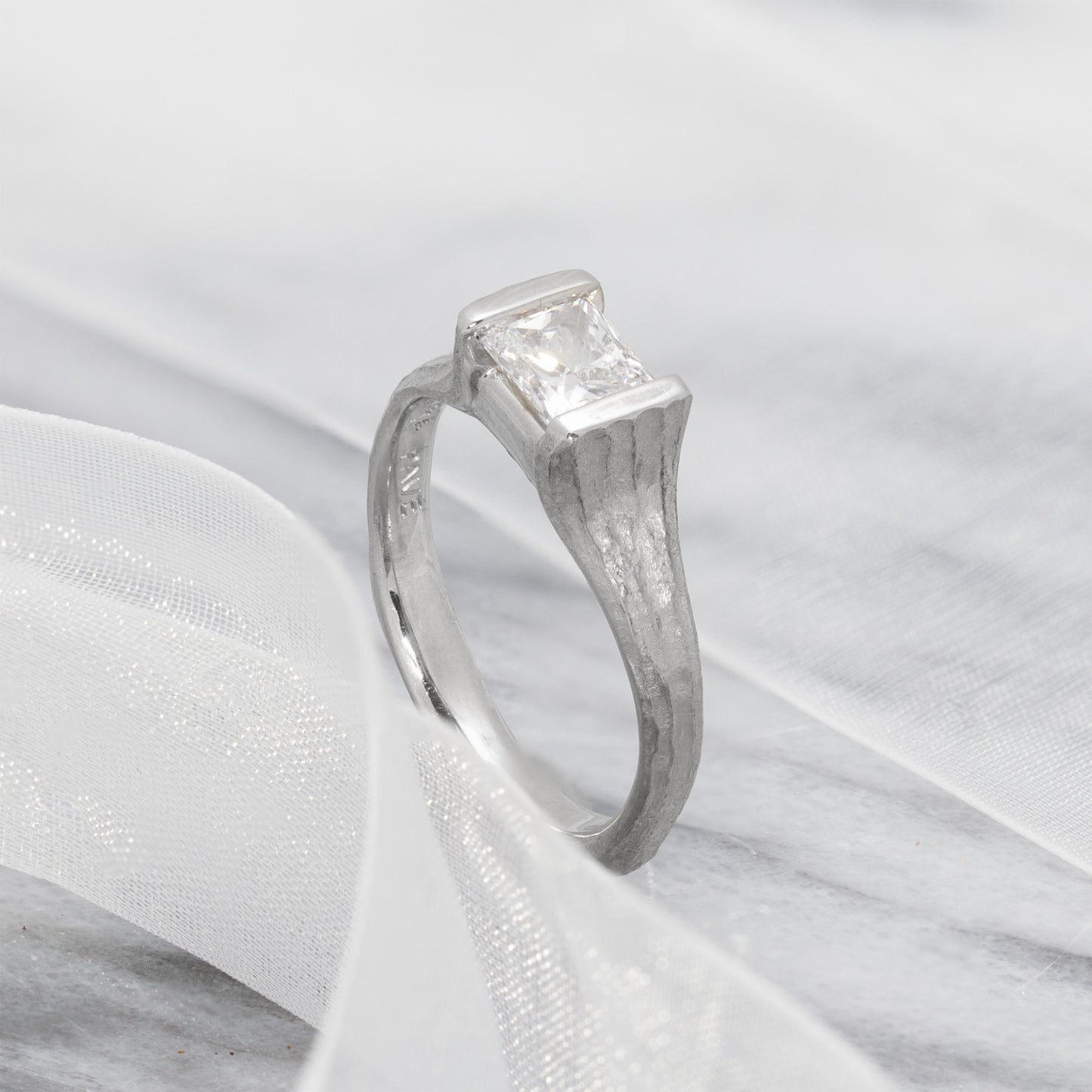 Platinum ring with a diamond on a white fabric background
