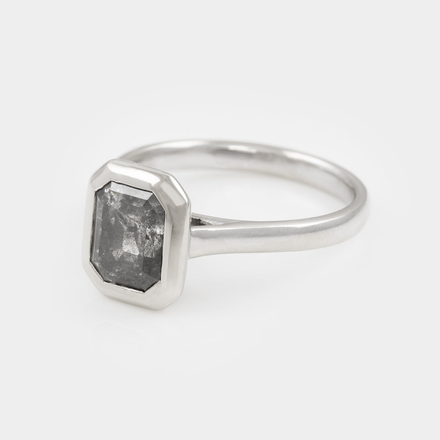 White gold ring with a large, salt and pepper diamond on a light gray background