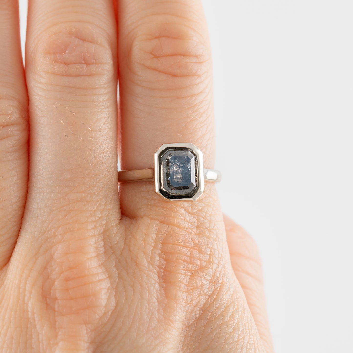 White gold ring with a large, dark gemstone on a hand